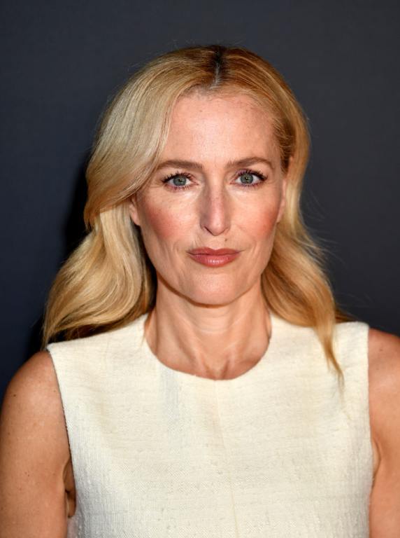 Gillian Anderson wearing a cream sleeveless dress with rosy cheeks.