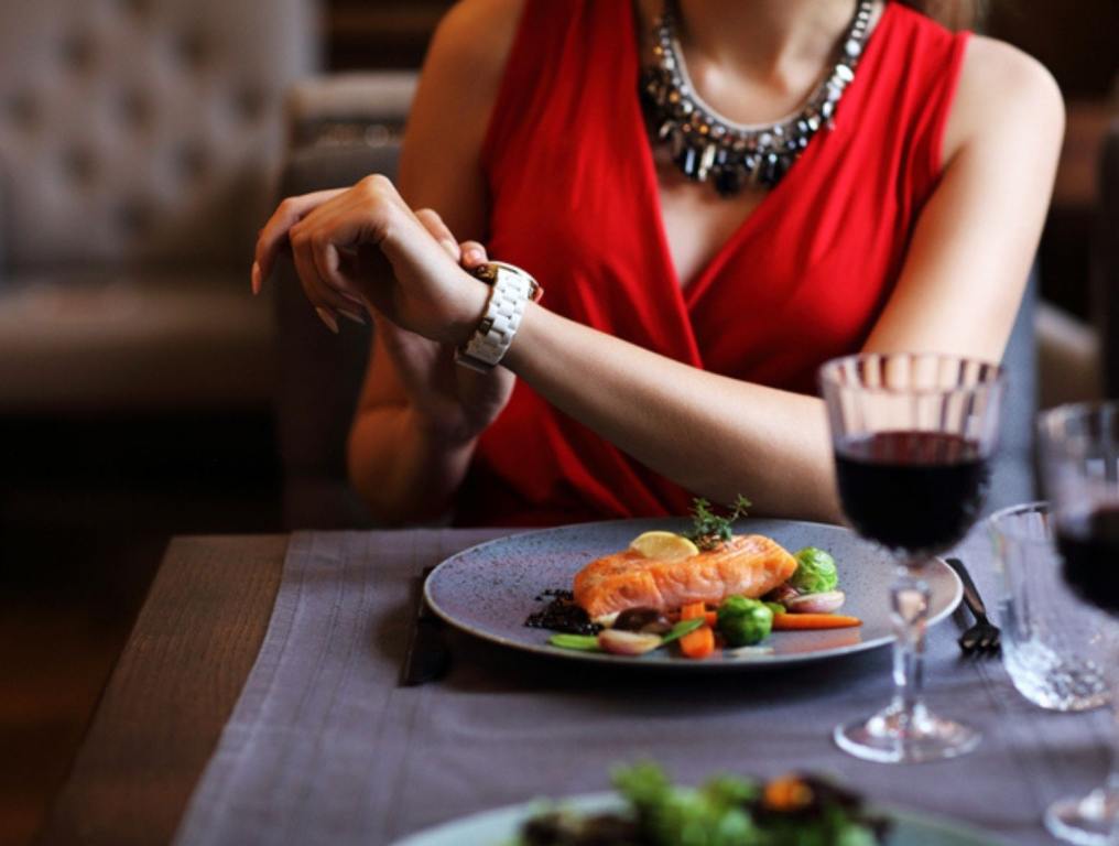 Woman looking at watch at restaurant waiting on date, ghost dates, ghosting concept.