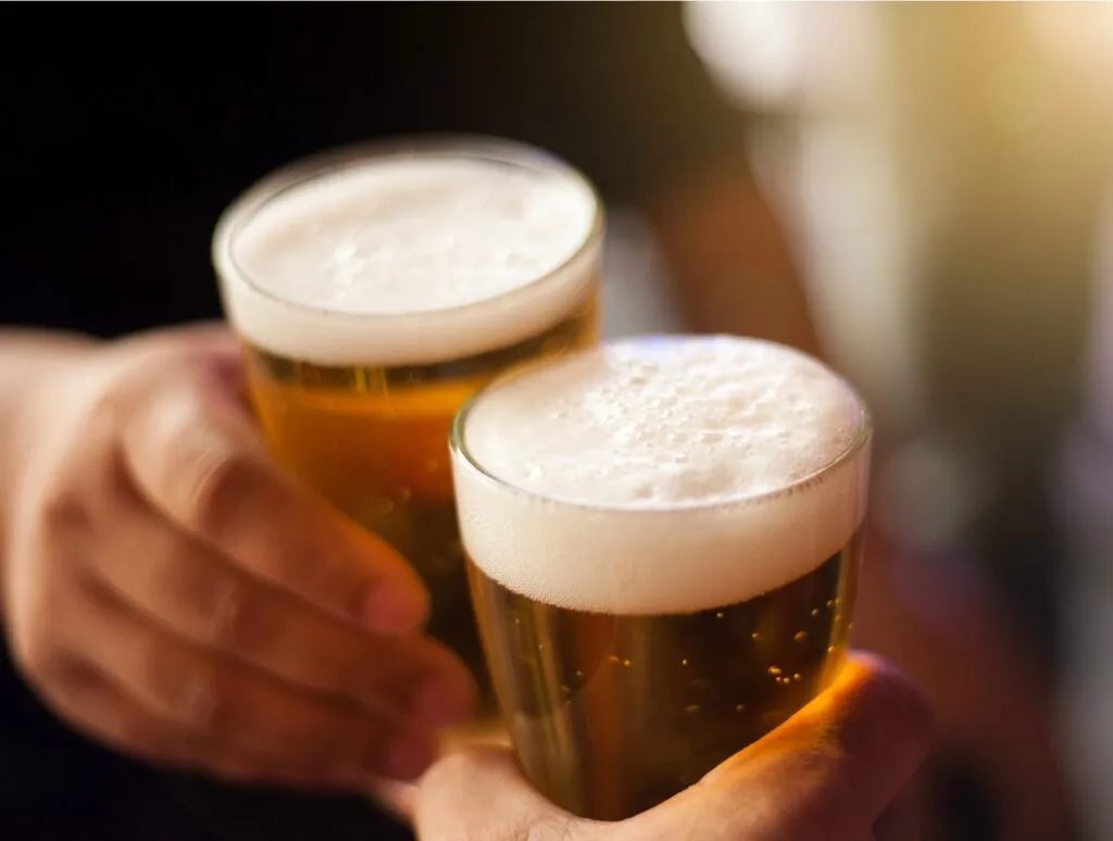 Cheers! Clink glasses. Close-up shots of hands holding beer glasses and beer bubbles (Michigan Beers).