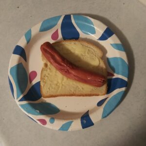 paper plate with a buttered slice of bread and a cooked hot dog