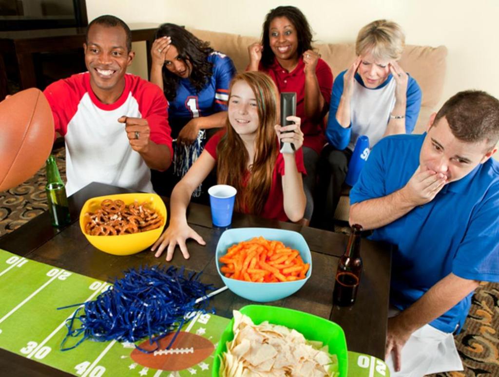 Diverse group of family and friends watching a football game with the red fan's team winning, Super Bowl party concept.