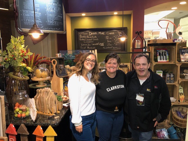 two women and a man smiling from uinside a business in Calrkston, Michigan talking about the upcoming Taste of Clarkston.