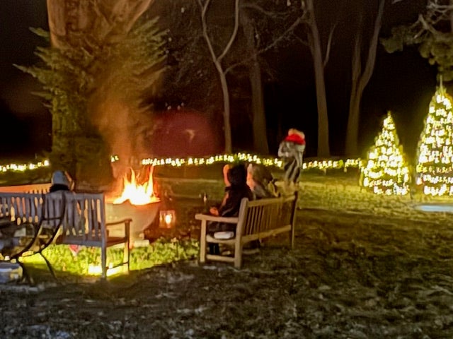 White Christmas lights and a nighttime bonfire on the grounds of the Ford House Home for the Holidays celebration.